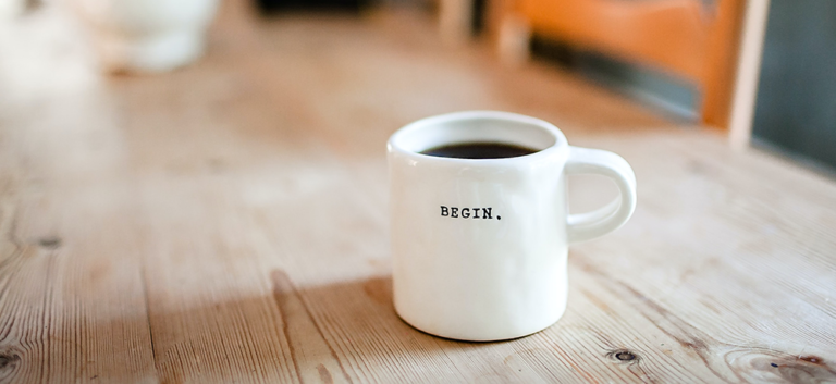 a white coffee cup with the word begin on it