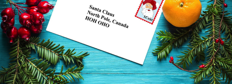 card addressed to santa claus on a blue table with fruits and pine branches
