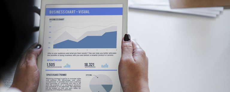 hands holding a tablet with business visual charts and numbers