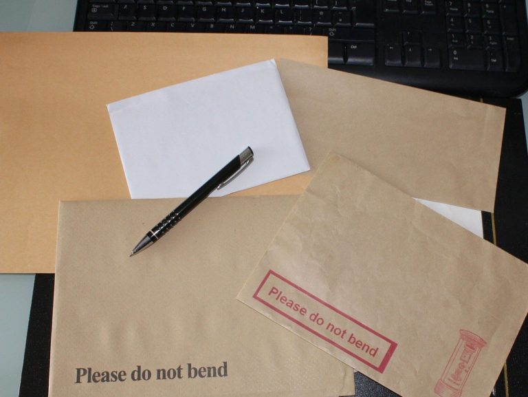desk filled with envelopes that all say please do not bend
