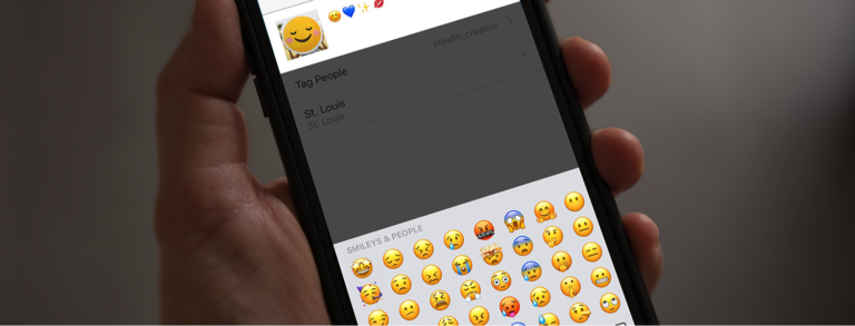 hand holding mobile phone with emoji selection screen