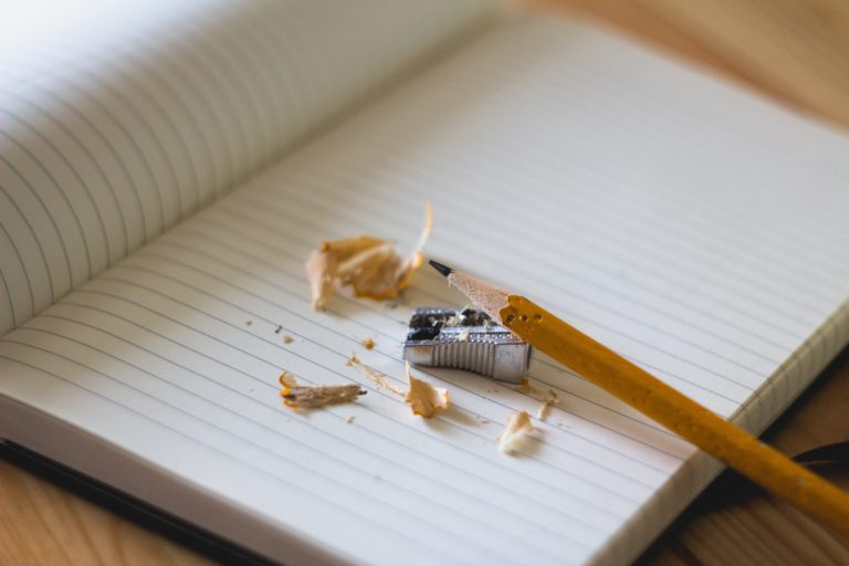 pencil with a pencil sharpener and shavings on a notebook