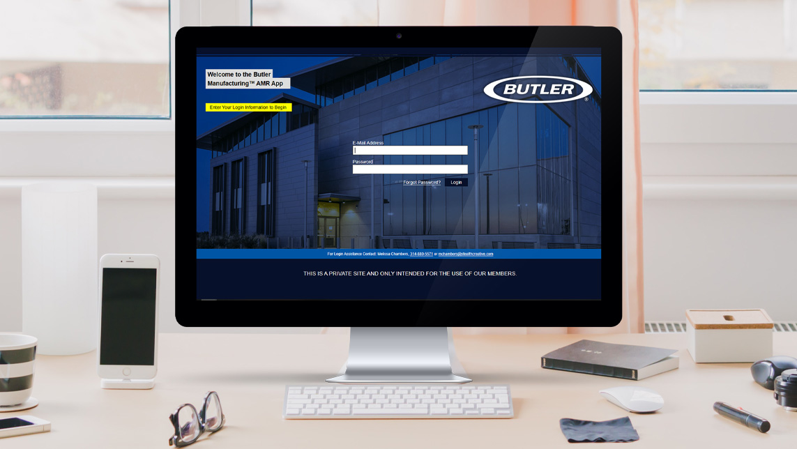 the butler manufacturing AMR app website on a screen sitting on a tan desk with a phone, keyboard and mouse around it